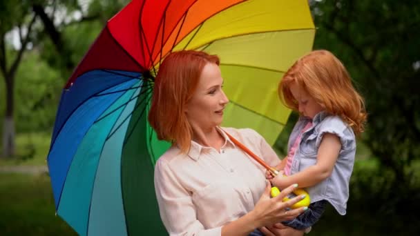 Happy mother and child under rainbow umbrella — Stock Video