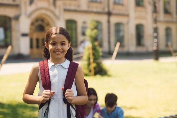 Красивая маленькая школьница, стоящая с рюкзаком — стоковое фото