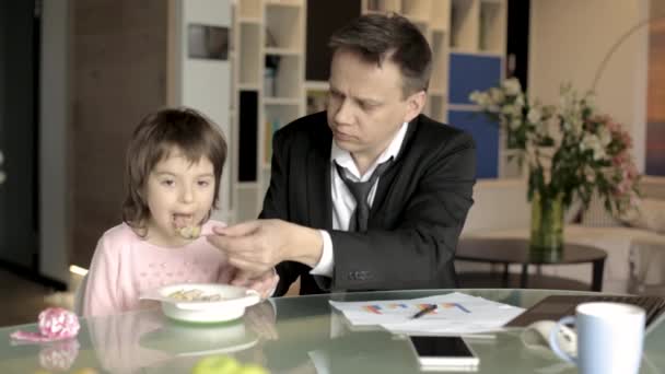 Работающий отец кормит маленькую дочь — стоковое видео