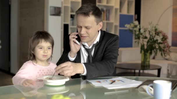 Father in suit working with papers and feeding daughter — Stock Video