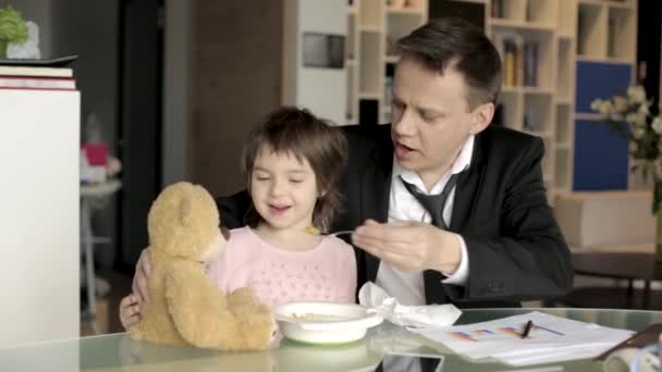 Работающий отец кормит маленькую дочь — стоковое видео