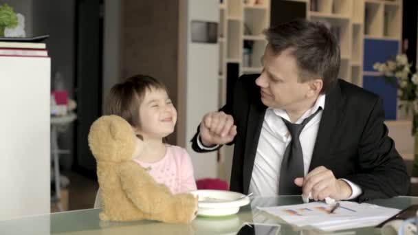 Padre en traje trabajando con papeles y alimentando a su hija — Vídeos de Stock