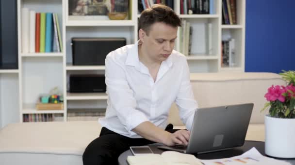 Мужчина работает на ноутбуке дома — стоковое видео