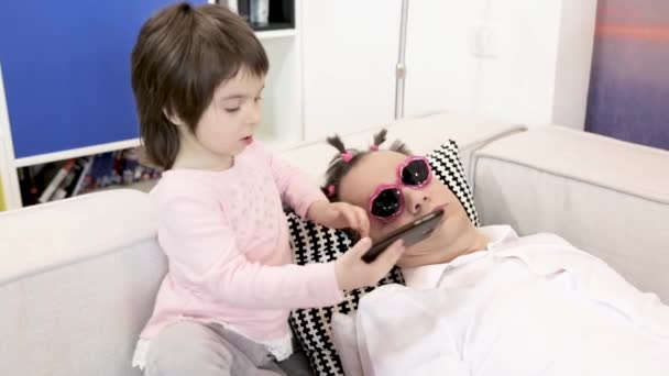 迷人的小女儿带着自己和睡觉的父亲在她应用化妆和一条马尾后 — 图库视频影像