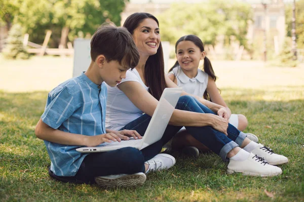 Leraar en twee jonge studenten laptop gebruikt in park — Stockfoto