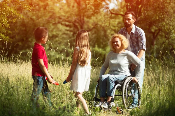 Smiling kids play with their disabled young mother — Stock Photo, Image