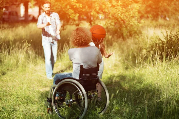Woman in wheelchair plays with ball with her family outdoors — Stock Photo, Image