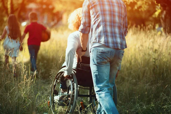 Man pushes woman in wheelchair to run after kids — Stock Photo, Image