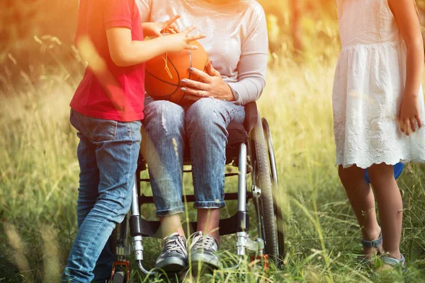 Joven mujer piernas en silla de ruedas con niños en voz alta su —  Fotos de Stock