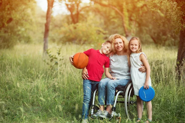 Familjeporträtt. Kvinna i rullstol med hennes familj utomhus. — Stockfoto