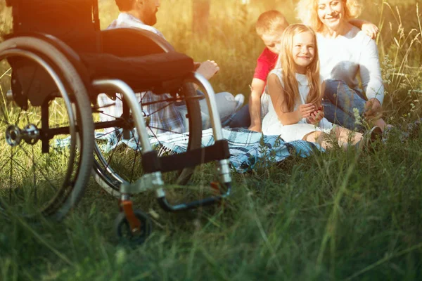 专注于在前景上的轮椅, 而幸福的家庭休息在后台 — 图库照片