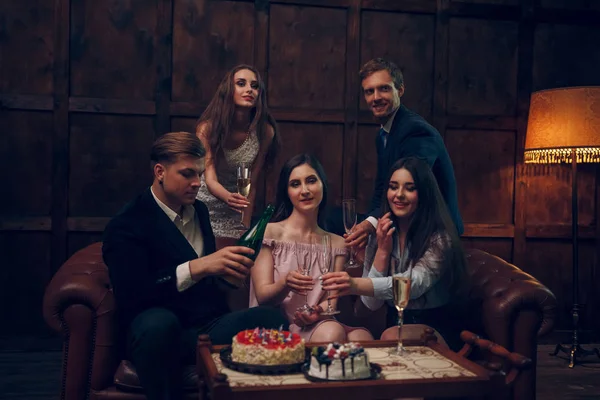 Amigos alegres celebram o aniversário bebendo champanhe e comendo bolo — Fotografia de Stock