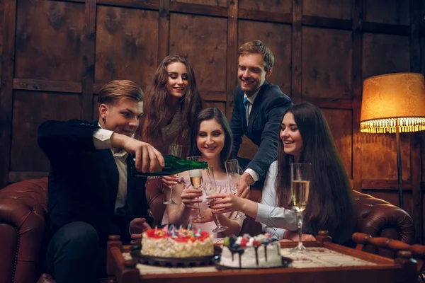 Веселі друзі святкують день народження, п'ють шампанське та їдять торт — стокове фото