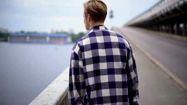 Ung man promenader längs bron — Stockvideo