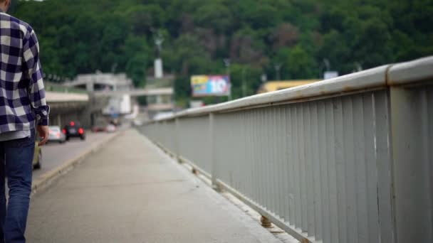 Jonge man wandelen langs de brug — Stockvideo