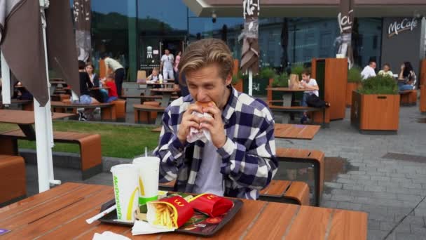 Un bărbat chipeș care mănâncă fast-food în Mc Donalds — Videoclip de stoc