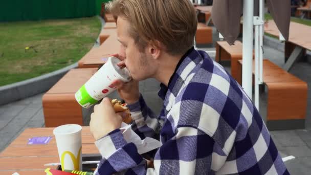 Красавчик, кушающий фаст-фуд в МакДональдсе — стоковое видео