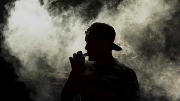 Un mec séduisant vaporise une ecigarette. Nuages de fumée — Video