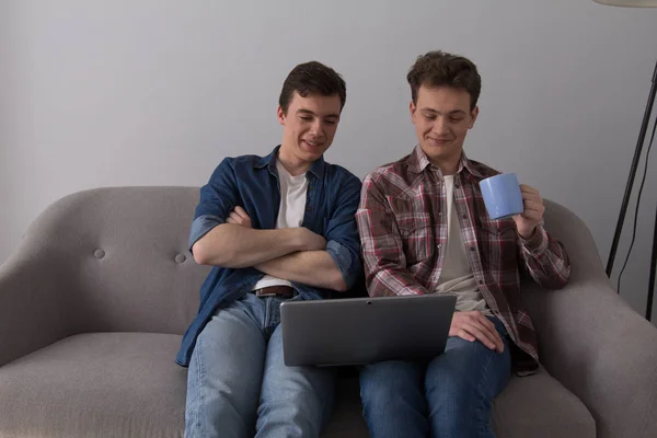 Dwóch facetów z laptopem na kanapie. — Zdjęcie stockowe
