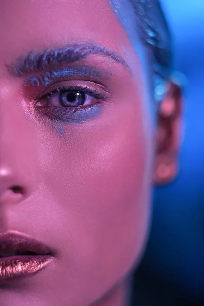 Het mooie gezicht van het meisje model met heldere blauwe ogen in een neon tint. — Stockfoto
