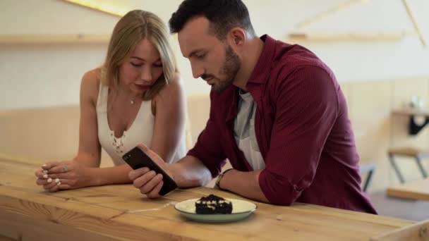 Guy ukazuje něco na svém telefonu do přítelkyně — Stock video