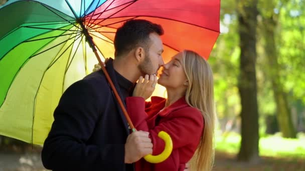 Close-up de casal romântico sob guarda-chuva arco-íris — Vídeo de Stock