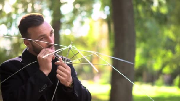 Attractive man fixes broken spokes of an umbrella. — Stock Video