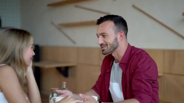 Jong koppel in liefde zitten in een cafe en met koffie — Stockvideo