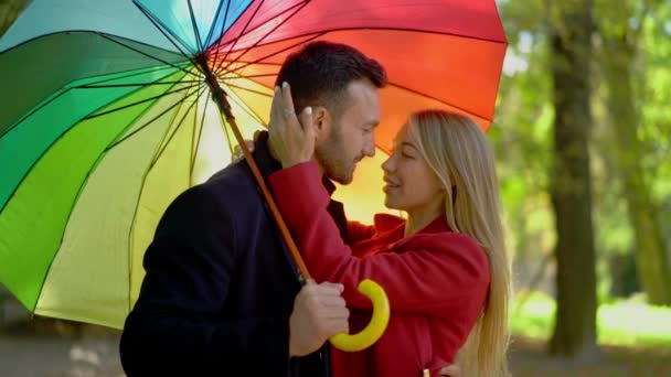 Casal sob guarda-chuva arco-íris andando no parque — Vídeo de Stock