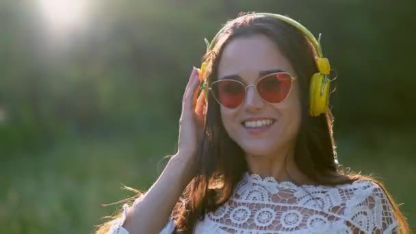 Menina bonita em uma imagem romântica Listens para fones de ouvido com música agradável . — Vídeo de Stock