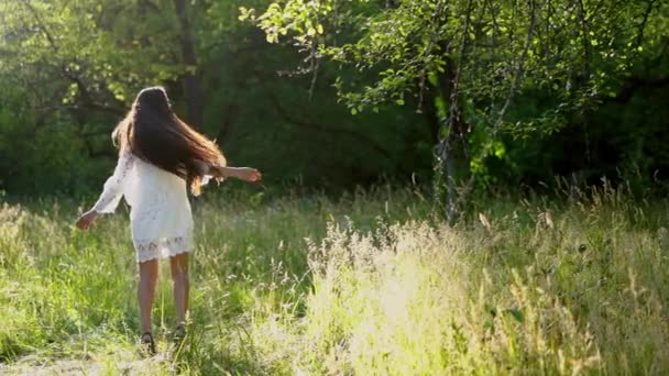 Прекрасна брюнетка дівчина крутиться навколо носіння білої сукні в парку — стокове відео