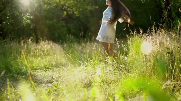 Härlig brunett flicka snurrar runt Iklädd vit klänning i parken — Stockvideo