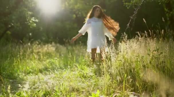 아름 다운 갈색 머리 소녀는 공원에서 흰색 드레스를 입고 주위를 돌면서합니다 — 비디오