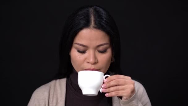 Brunette vrouw drinken koffie met een witte kop. — Stockvideo