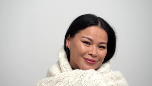 Leuke Aziatische vrouw op een witte achtergrond voorzichtig nemen hun toevlucht in een witte sjaal. — Stockvideo
