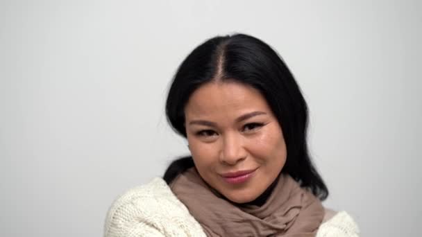 Mooie Aziatische vrouw met een zoete glimlach en smalle ogen op een witte achtergrond. — Stockvideo