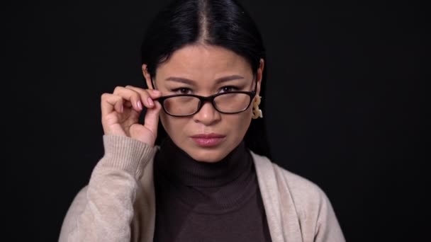 Pensando asiático mujer de negocios en gafas en oscuro fondo — Vídeo de stock