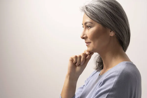 Pensive woman is touching chin and slightly smiles — Stock Photo, Image