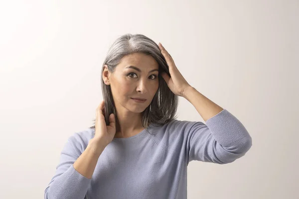 Volwassen vrouw van de Mongoolse nationaliteit met grijze haren op een witte achtergrond. — Stockfoto