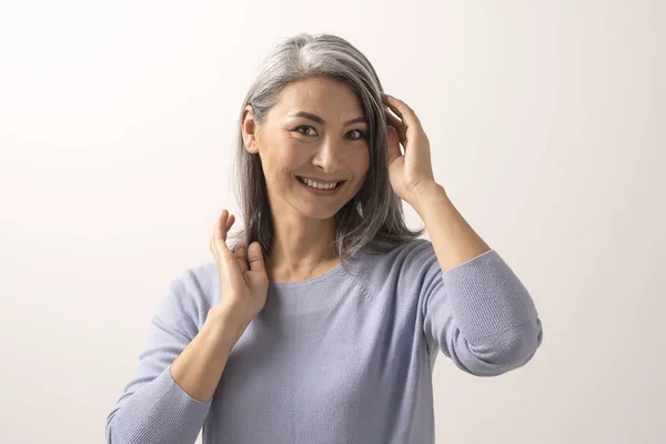 Smiling Asian woman touches her grey hair — Stock Photo, Image