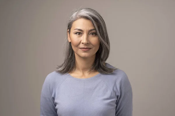 Schöne mongolische Frau mit grauen Haaren auf grauem Hintergrund. — Stockfoto