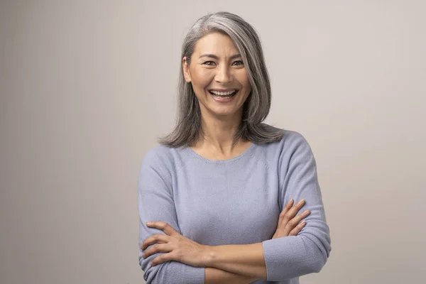 Fröhliche mongolische Frauen mit grauen Haaren vor grauem Hintergrund. — Stockfoto