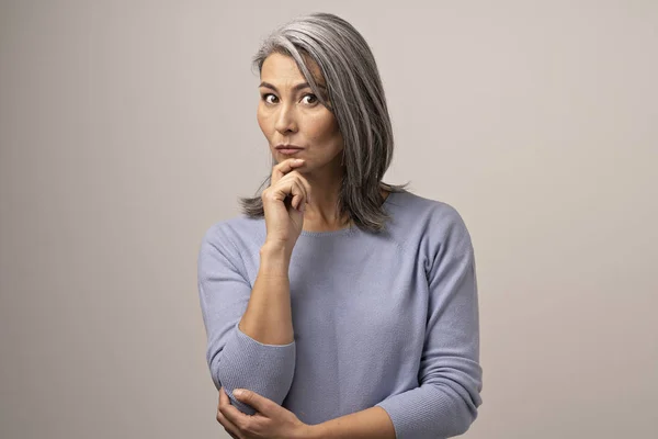 A Mongolian-Looking Woman with Gray Hair Looks Thoughtfully Into the Frame. — Stock Photo, Image