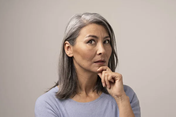 Mujer mongola adulta con el pelo gris sobre un fondo gris . — Foto de Stock