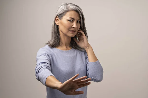 Een sombere Mongoolse vrouw met grijze haren tegen een grijze achtergrond. — Stockfoto