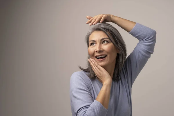 Mulher feliz com aparência mongol cabelo cinza no fundo cinza . — Fotografia de Stock