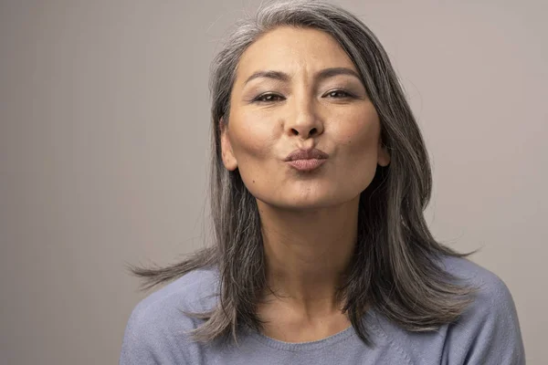 Charmante mongolische Frau mit grauen Haaren vor grauem Hintergrund. — Stockfoto