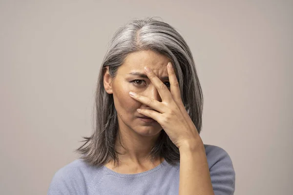 Kvinnan av mongoliska utseende med en sorgsen blick på en grå bakgrund. — Stockfoto