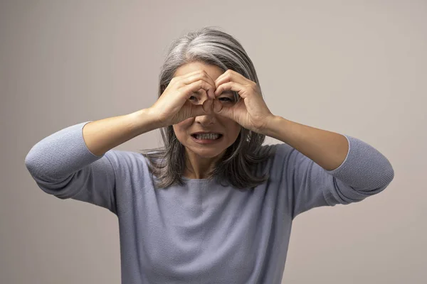 Asiática madura mujer does ok gesto como binoculares . —  Fotos de Stock