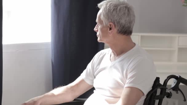 Volwassen Man met grijs haar in een rolstoel in het ziekenhuis. — Stockvideo